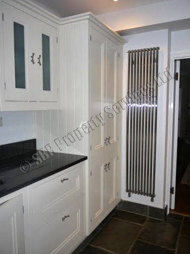 Luxury handmade bespoke kitchen in Exeter with Fired Earth flagstone slate tiles, black granite worktops, and an American-style fridge freezer by SBR Property Services Ltd.