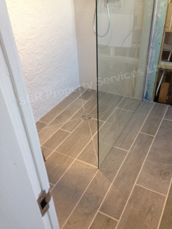 Contemporary Porcelanosa shower room in Exeter with concealed shower valve, towel rail, and wet underfloor heating by SBR Property Services Ltd.