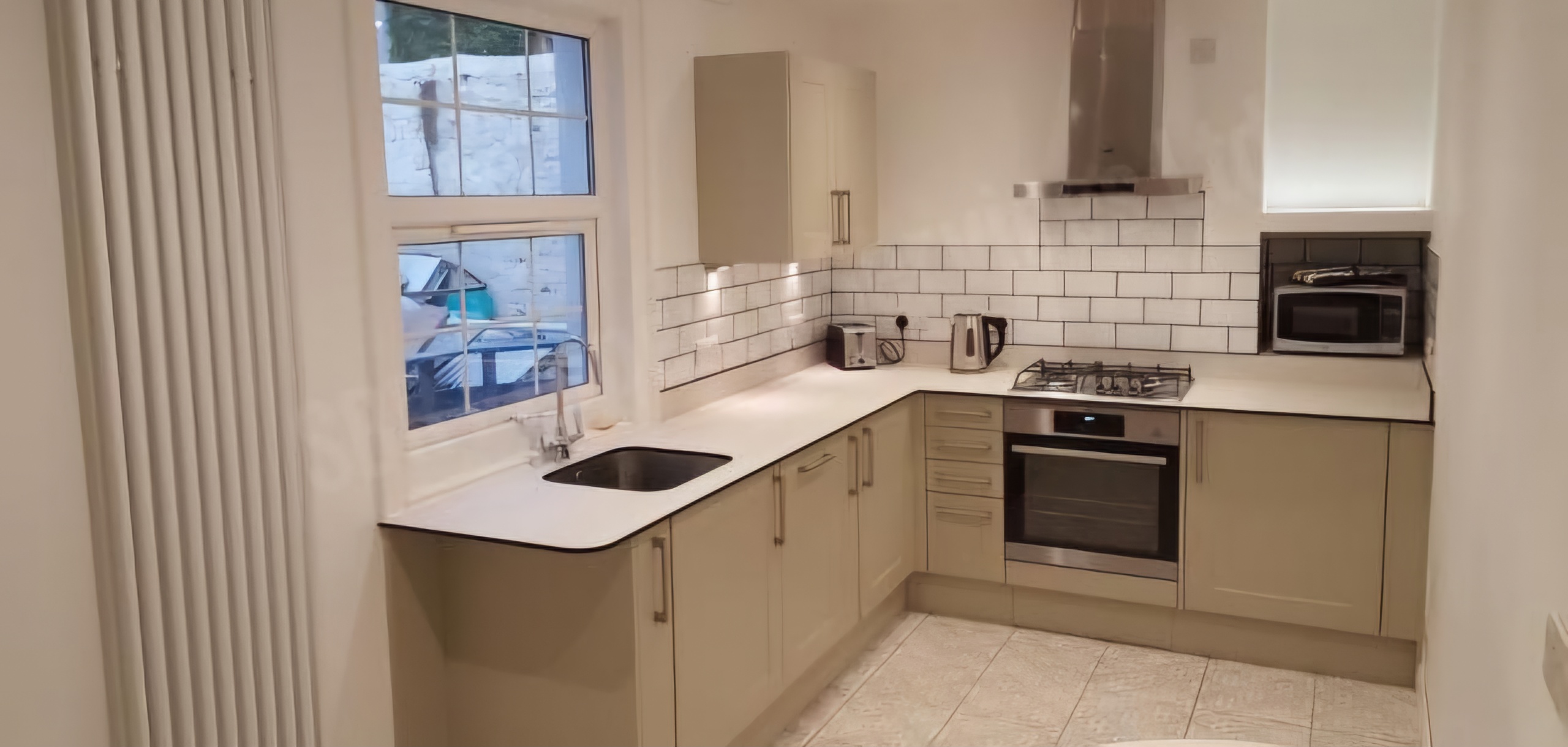 Budget-friendly modern shaker-style kitchen in Exeter with a composite worktop, Victorian-style floor tiles, and an under-counter sink by SBR Property Services Ltd.