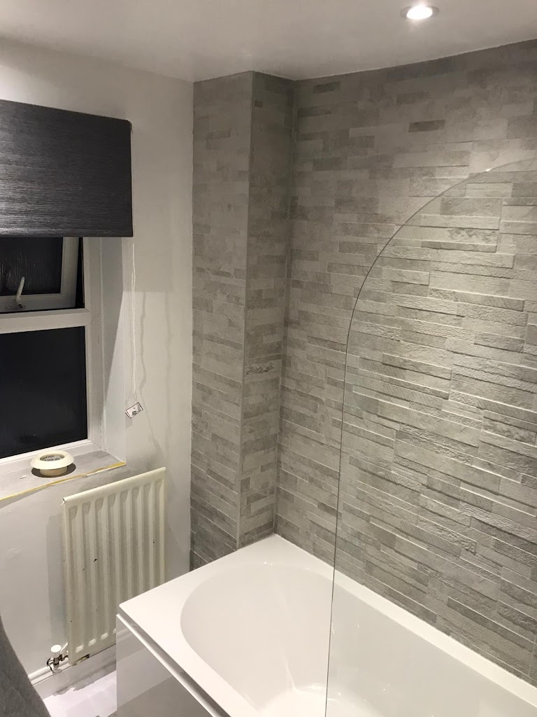 Contemporary en-suite bathroom in Exeter featuring a black wall-hung basin with drawers, a bath with a shower screen, and LED downlights by SBR Property Services Ltd.