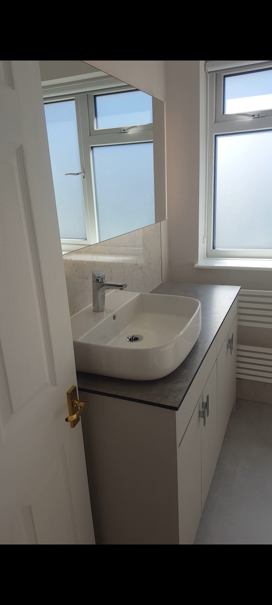 High-tech modern bathroom in Exeter featuring a Bluetooth mirror with LED lights and speakers, shower panels, and silver-flecked vinyl flooring by SBR Property Services Ltd.