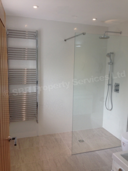 High-end Porcelanosa bathroom in Exeter with concealed thermostatic shower valve, towel rail, and wet underfloor heating by SBR Property Services Ltd.