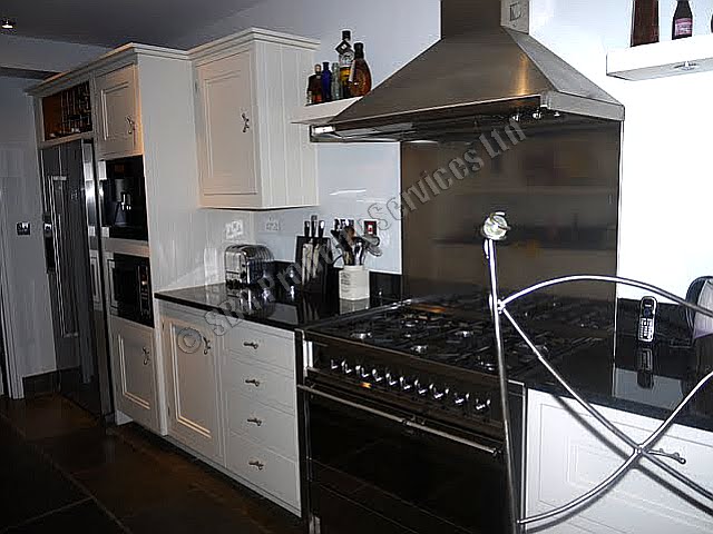 Custom handmade kitchen in Exeter with a gas range cooker, integrated Miele coffee machine, Belfast sink, and wine rack by SBR Property Services Ltd.