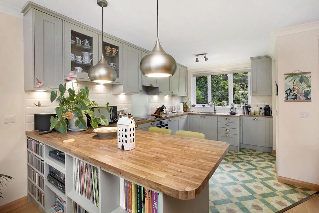 Luxury olive green shaker kitchen in Exeter with cream metro tiles, a bespoke record player, and vinyl storage built into the breakfast bar by SBR Property Services Ltd.