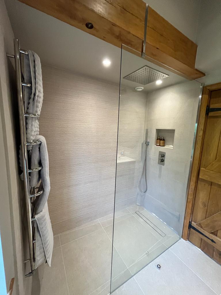 Modern wetroom with frameless glass shower screen and ceiling-mounted waterfall shower head. By SBR Property Services Ltd.