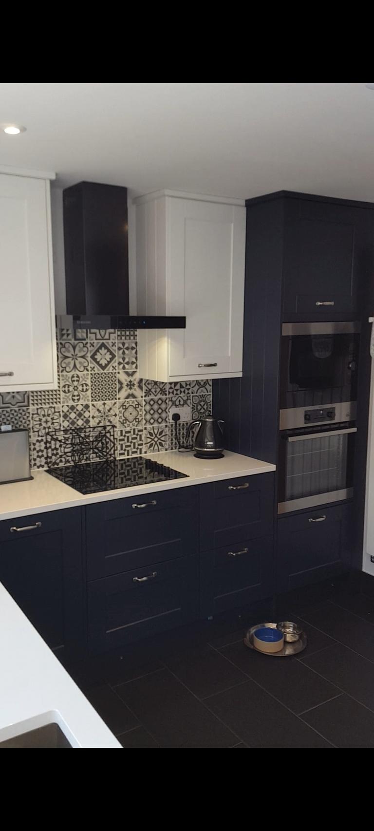 Stylish blue and white shaker kitchen in Exeter with Victorian-style flooring, white quartz countertops, and an AEG ComfortLift dishwasher by SBR Property Services Ltd.