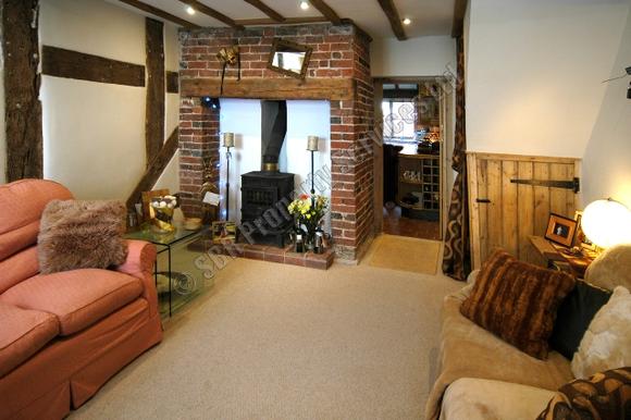 Restored small terraced listed cottage in Exeter featuring an inglenook fireplace, wood-burning stove, and lime-plastered oak beams, expertly renovated by SBR Property Services Ltd.